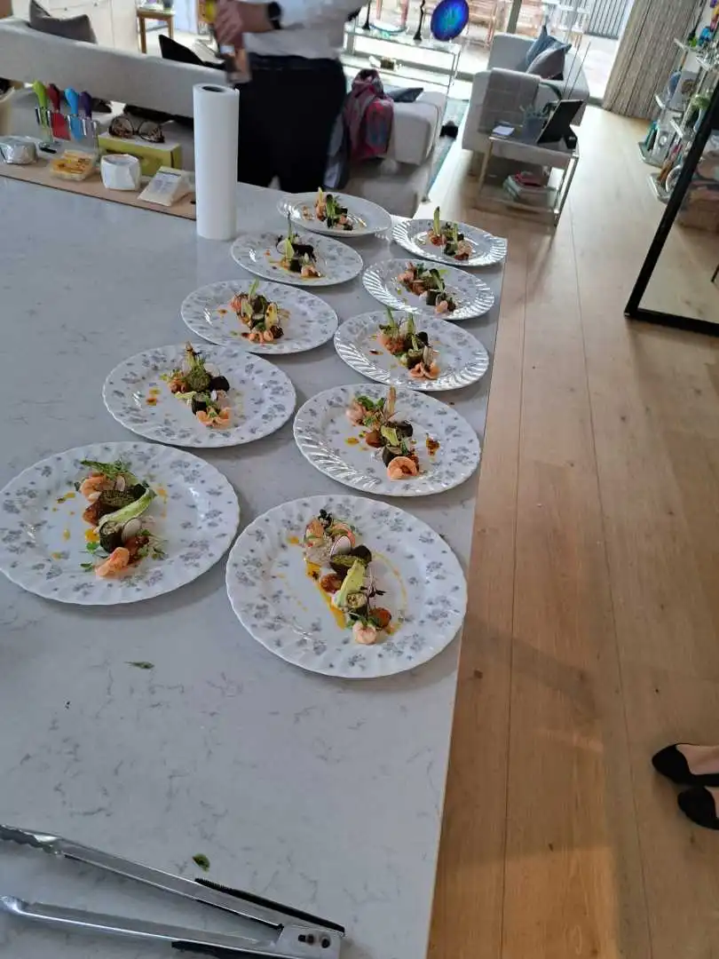 Ten plated prawn and beetroot starters on floral plates lined up on a marble island for a private catered dinner in Bournemouth