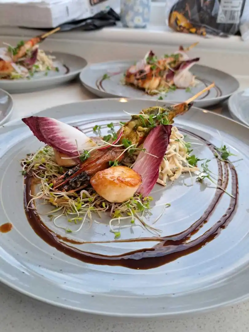 Seared scallop and herb-crusted prawn skewer on sprouts with radicchio and balsamic reduction plated for a private catered event in Bournemouth