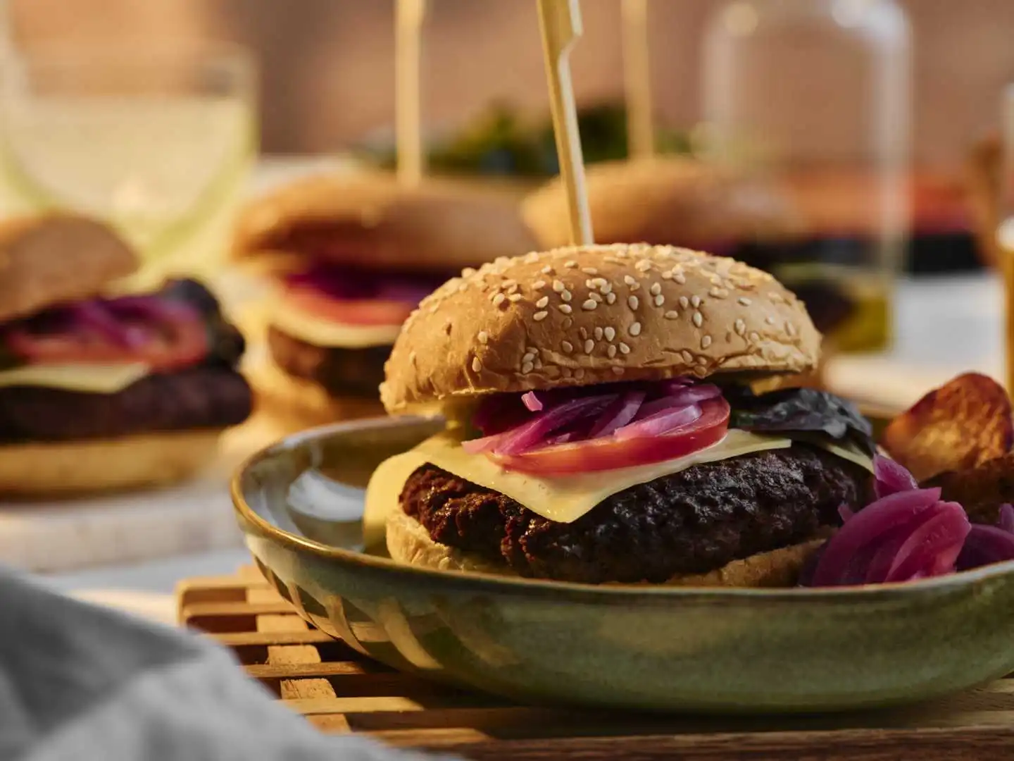 Close up side profile of a charred beef smash burger with melted cheese and pickled red onions in a sesame bun at a Bournemouth catered event